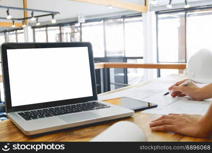 image of engineer hands discussing a building construction project with blank screen laptop at workplace