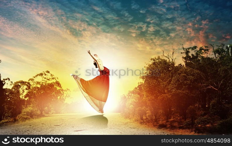 Image of female ballet dancing outdoor against sunset background. Female ballet dancer