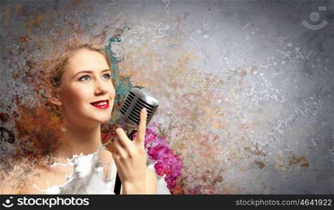 Image of female blond? singer holding microphone against color background
