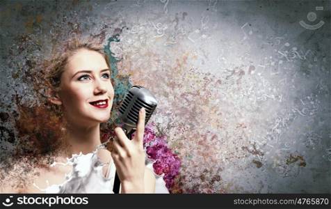 Image of female blond? singer holding microphone against color background