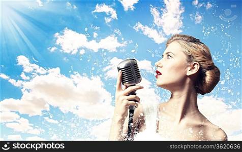 Image of female blonde singer holding microphone against clouds background