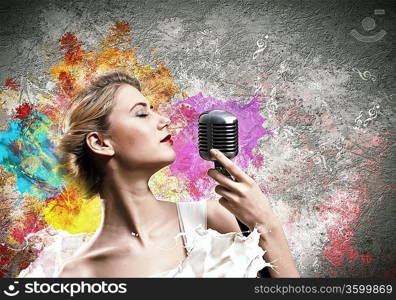 Image of female blonde singer holding microphone against color background with closed eyes