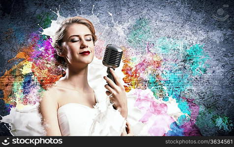 Image of female blonde singer holding microphone against color background with closed eyes
