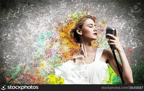 Image of female blonde singer holding microphone against color background with closed eyes