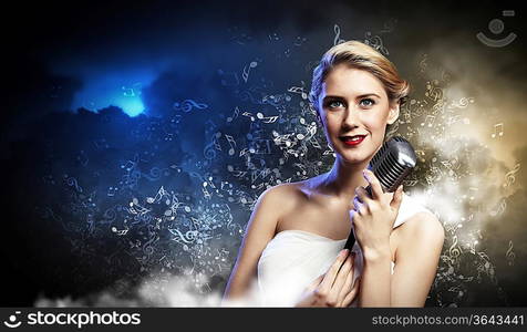 Image of female blonde singer holding microphone against smoke background