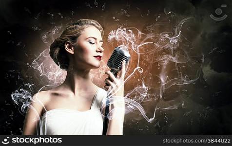 Image of female blonde singer holding microphone against smoke background with closed eyes