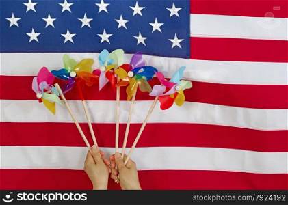image of female hands holding twirlers with United States of America flag in background. Fourth of July holiday concept.