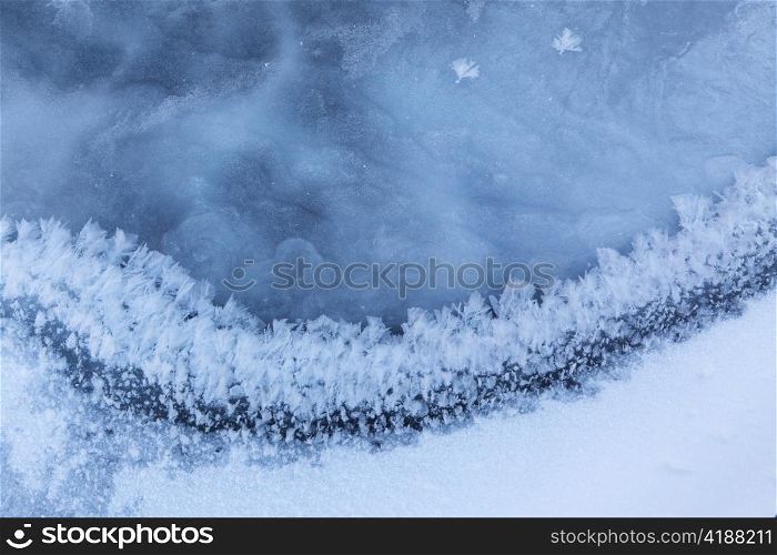 Image of frozen lake with ice edge covered with big icy snowflakes