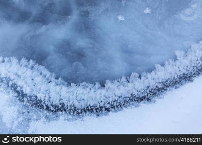 Image of frozen lake with ice edge covered with big icy snowflakes