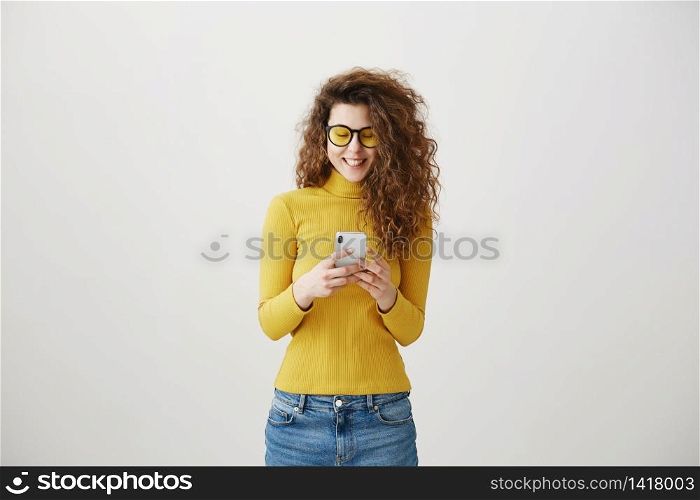 Image of gorgeous woman in casual being surprised or excited to receive pleasant text message on her cell phone, over gray background. Image of gorgeous woman in casual being surprised or excited to receive pleasant text message on her cell phone, over gray background.