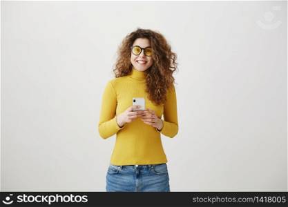 Image of gorgeous woman in casual being surprised or excited to receive pleasant text message on her cell phone, over gray background. Image of gorgeous woman in casual being surprised or excited to receive pleasant text message on her cell phone, over gray background.