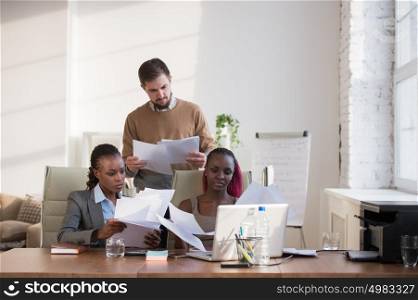Image of group of three young business people of different ethnicity working together