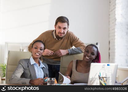 Image of group of three young business people using laptop at meeting