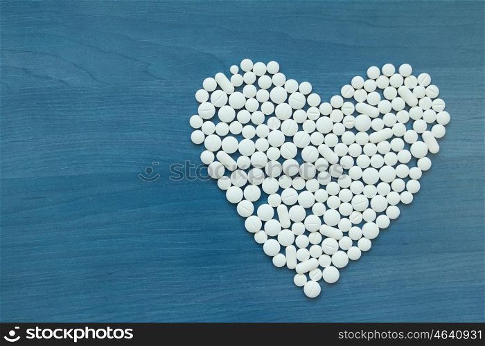 Image of heart made up out of white tablets on the blue background