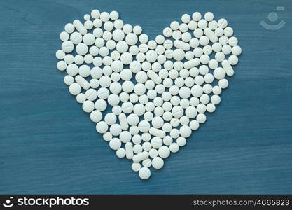 Image of heart made up out of white tablets on the blue background