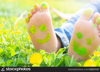 Image of human foots in colorful paint with smiles.Child lying on green grass.asian kid having fun outdoors in spring park