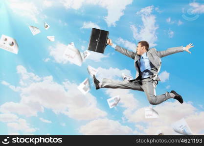 Image of jumping businessman. Image of a businessman jumping high against blue sky background