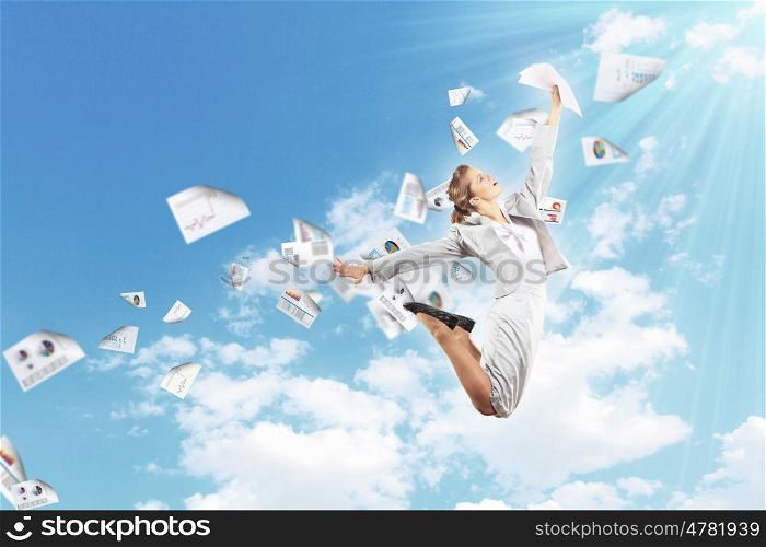 Image of jumping businesswoman. Image of a businesswoman jumping high against blue sky background