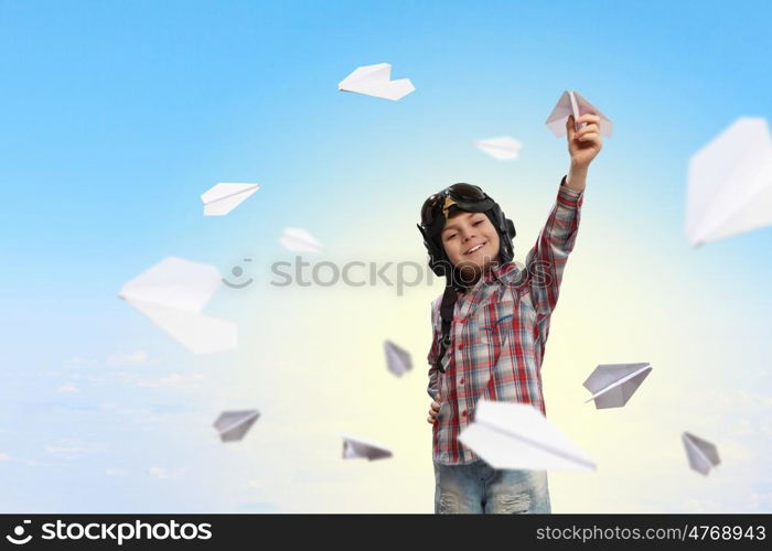 Image of little boy in pilots helmet playing with paper airplane