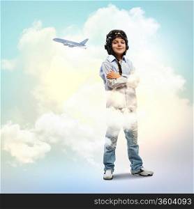 Image of little boy in pilots helmet with flying airplane in background