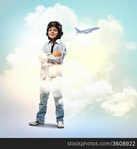 Image of little boy in pilots helmet with flying airplane in background