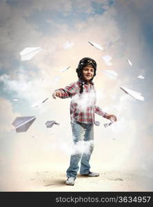 Image of little boy in pilots helmet with paper airplanes in background