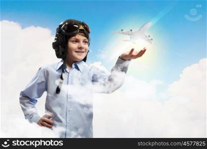 Image of little boy in pilots helmet with toy airplane in hand