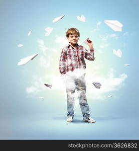 Image of little boy playing with paper airplane against blue background