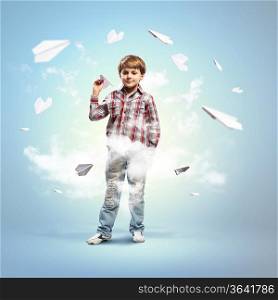 Image of little boy playing with paper airplane against blue background