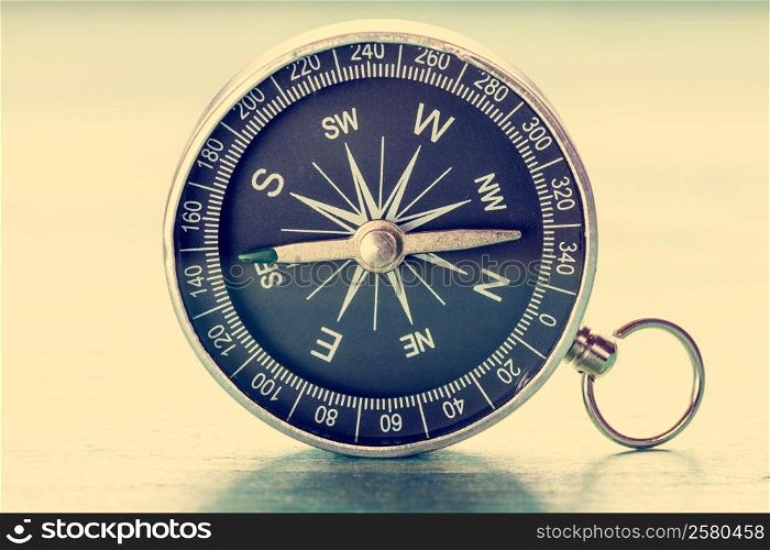 Image of old compass on wooden background. Vintage filtered and toned.