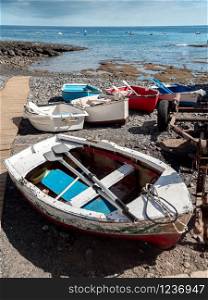 Image of old painted wooden rowing boats lying on the sea beach next to the pier. Photo of old painted wooden rowing boats lying on the sea beach next to the pier