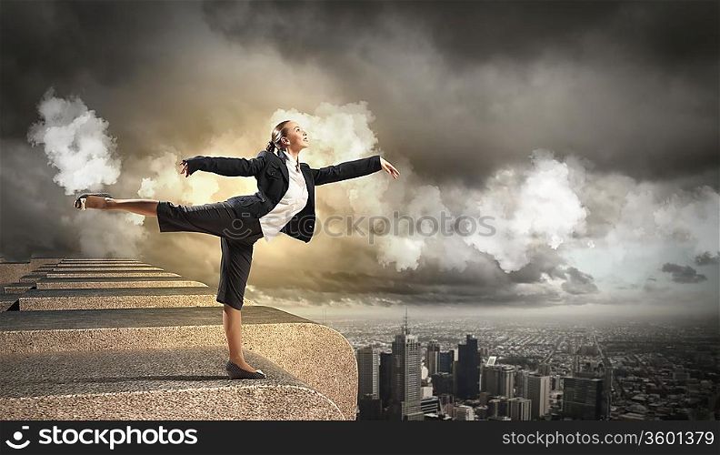 Image of pretty businesswoman balancing on the roof above cityscape