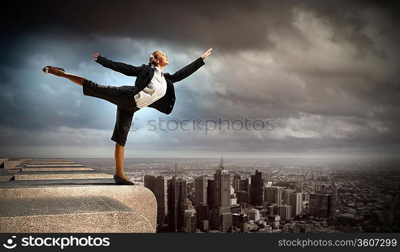 Image of pretty businesswoman balancing on the roof above cityscape