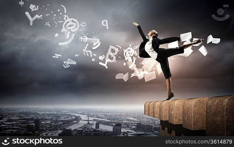 Image of pretty businesswoman balancing on the roof above cityscape