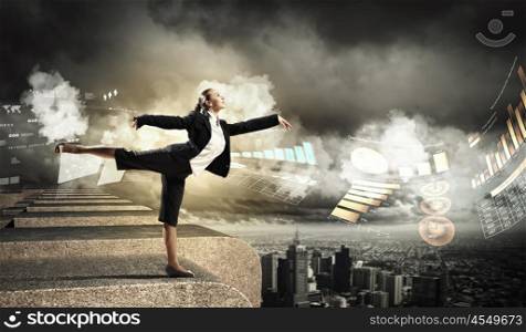 image of pretty businesswoman. Image of pretty businesswoman balancing on the roof above cityscape