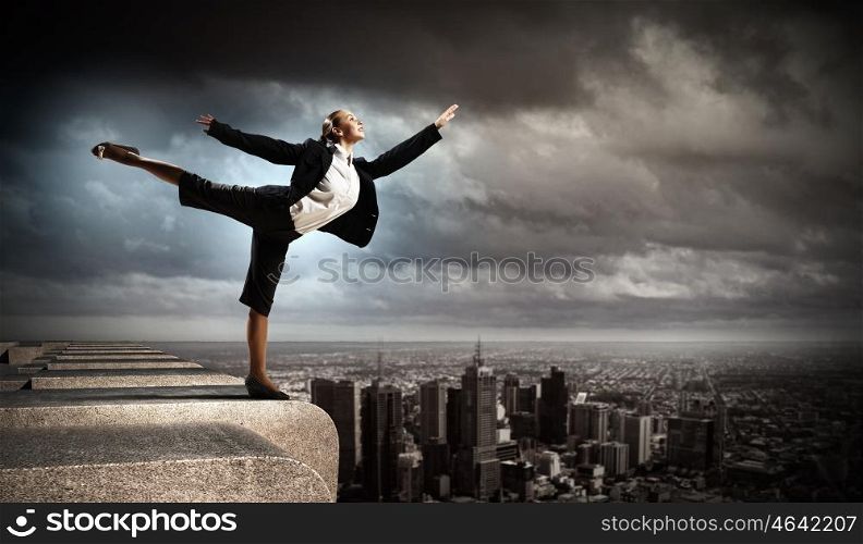 image of pretty businesswoman. Image of pretty businesswoman balancing on the roof above cityscape