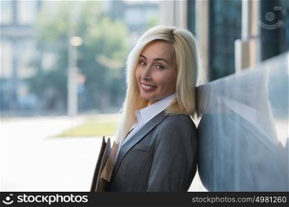Image of pretty businesswoman looking at camera and holding documents outdoor
