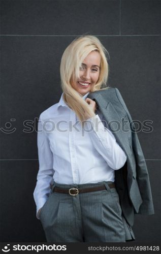 Image of pretty businesswoman smiling and leaning on wall outdoor