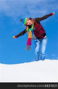 Image of pretty playful female having fun in winter park, cute woman standing with raised up hands on the top of snowy mountain, colorful hat and scarf, wintertime holidays, freedom concept&#xA;