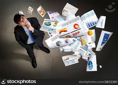 Image of printed materials flying in air top view against businessman background