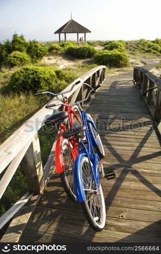 Image of red and blue bike leaning against railing of boardwalk.