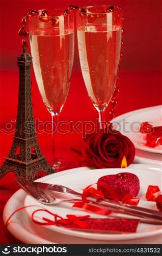 Image of red luxury table setting, white festive plate and two glass of champagne decorated with small Eiffel tower and fresh rose flower, dinner in Paris, honeymoon in France, Valentine day&#xA;