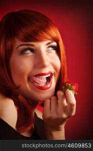 Image of seductive redhead girl holding in hand fresh strawberry, closeup portrait of sexy woman with open mouth eat juicy fruit isolated on red background, Valentine day, passion concept