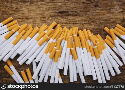 image of several commercially made pile cigarette on wooden background. or Non smoking campaign concept, tobacco pattern top view.