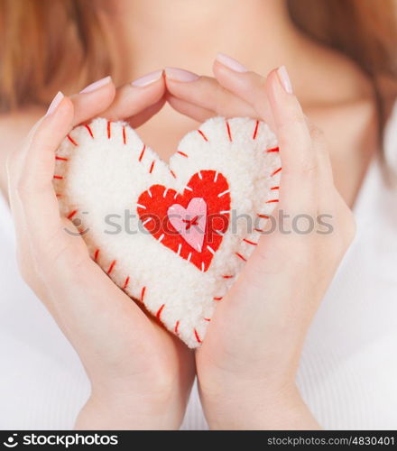 Image of sewn white heart with red decorations in woman's palms, beautiful handmade soft toy heart-shaped, romantic gift, winter holiday for lovers, healthy lifestyle, love and affection concept&#xA;