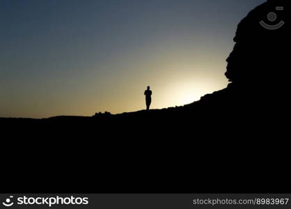 Image of the silhouette of a man on a rock with the sun backlit, silhouette of a person on a rock, entrepreneurship concept