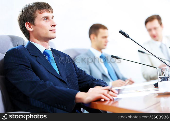 Image of three businesspeople at table at conference