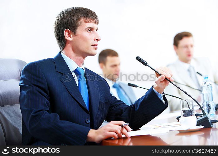 Image of three businesspeople at table at conference