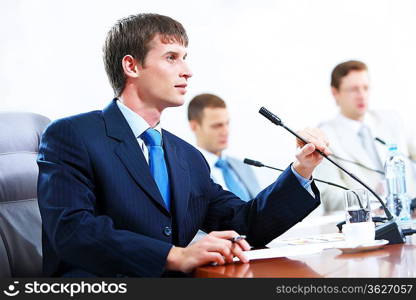 Image of three businesspeople at table at conference