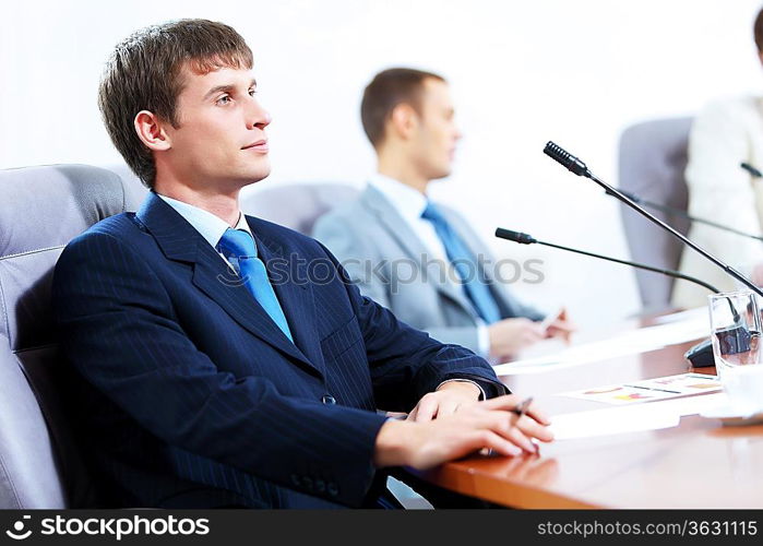 Image of three businesspeople at table at conference